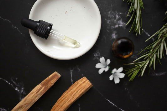 Essential oil next to herbs and flowers